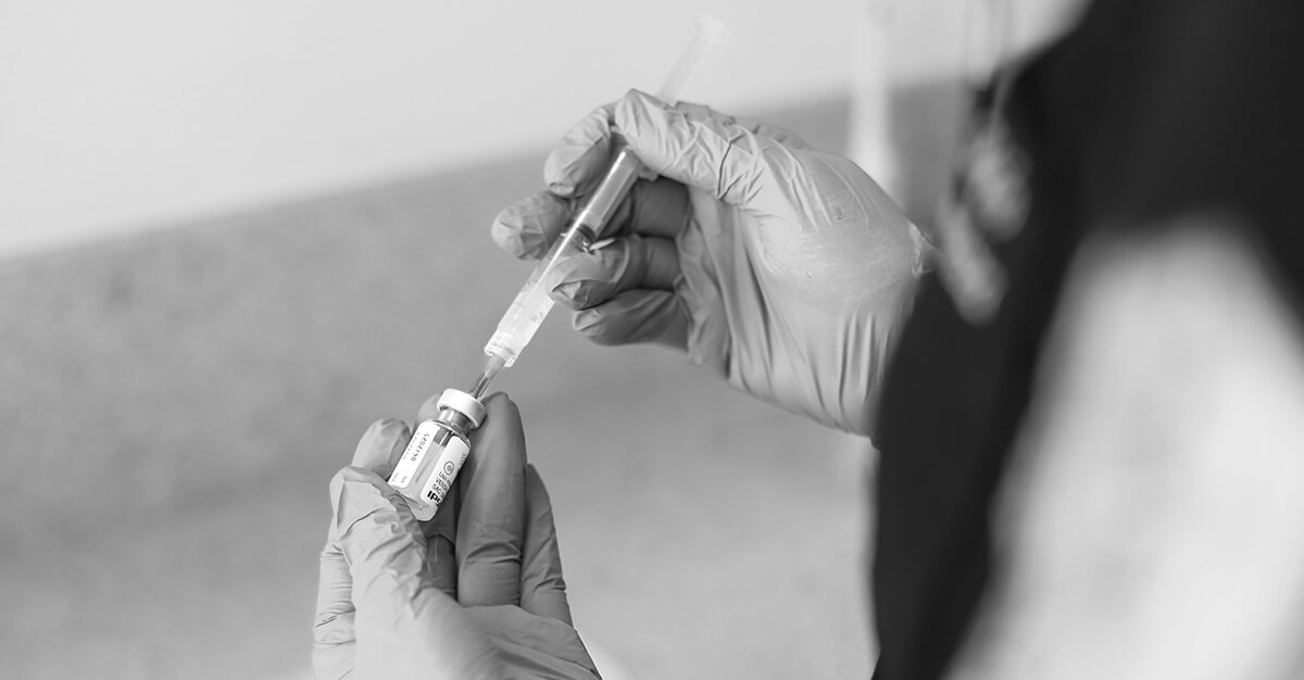 A person in gloves holding a syringe in their hand