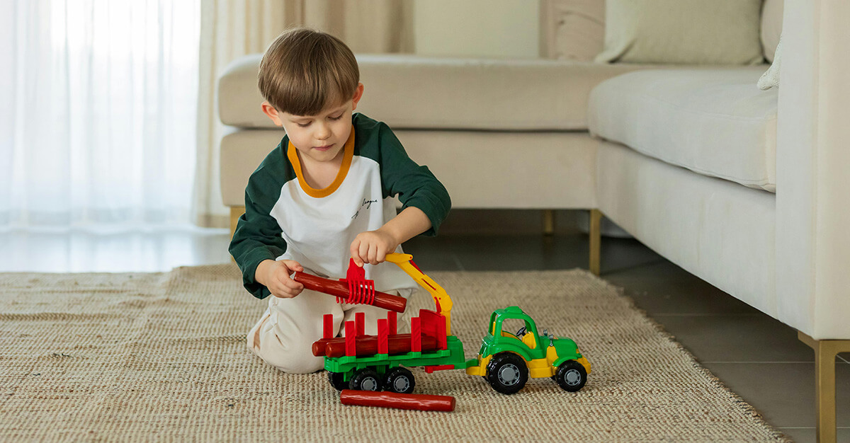 Young Boy Playing with Toy Tractor Indoors